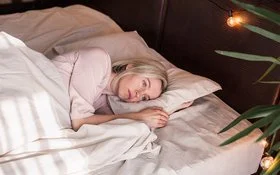 Eine Frau liegt mit offenen Augen im Bett und schaut nachdenklich.