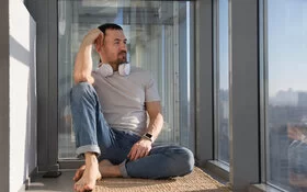 Ein Mann sitzt auf dem Boden und schaut aus dem Fenster. 