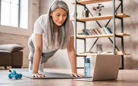 Frau mittleren Alters ist Fitness-Anfängerin und macht ein Workout im Wohnzimmer.