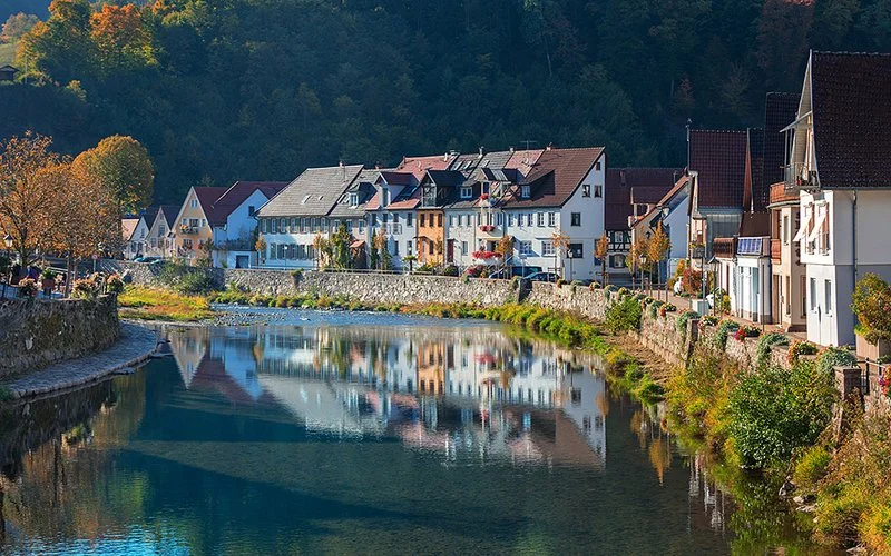 Fluss Kinzig fließt durch eine Stadt, am Ufer stehen Häuser mit Blick aufs Wasser.