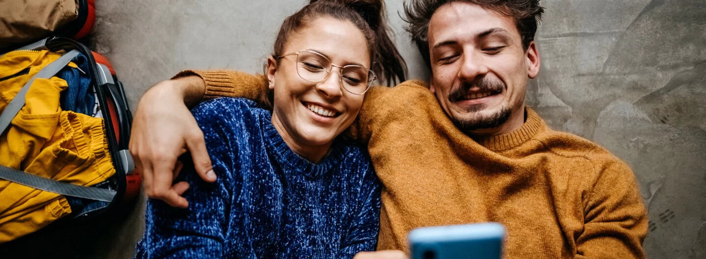Frau und Mann liegen auf den Rücken und telefonieren mit der AOK.