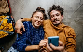 Frau und Mann liegen auf den Rücken und telefonieren mit der AOK.