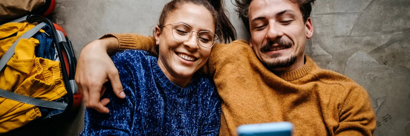 Frau und Mann liegen auf den Rücken und telefonieren mit der AOK.