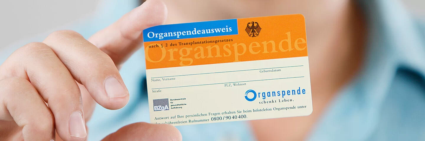 Ein nicht erkennbarer Mann hält einen Organspendeausweis mit der rechten Hand in die Kamera.