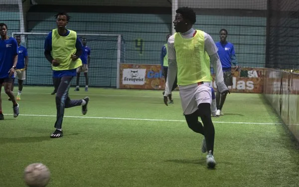 Junge Männer spielen Fußball auf einem Fußballplatz.