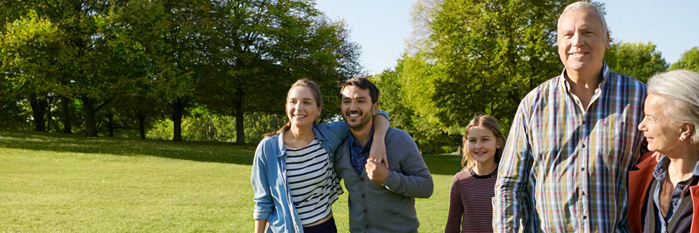 Eine Gruppe von Personen unterschiedlicher Generationen geht über eine Parkwiese und lächelt zuversichtlich in die Kamera. Der Wechsel der Krankenkasse ist leichter, als man denkt.