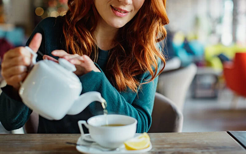 Eine Frau gießt sich Tee in eine Tasse ein.