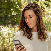 Eine Frau blickt auf ihr Smartphone. Mit der AOK-Bonus-App kann sie Punkte sammeln.