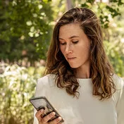 Eine Frau blickt auf ihr Smartphone. Mit der „Meine AOK“-App und dem Bonusprogramm kann sie Punkte sammeln.