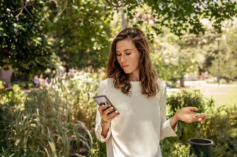 Eine Frau blickt auf ihr Smartphone. Mit der AOK-Bonus-App kann sie Punkte sammeln.