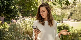 Eine Frau blickt auf ihr Smartphone. Mit der „Meine AOK“-App und dem Bonusprogramm kann sie Punkte sammeln.