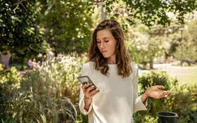 Eine Frau blickt auf ihr Smartphone. Mit der „Meine AOK“-App und dem Bonusprogramm kann sie Punkte sammeln.