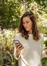 Eine junge Frau blickt auf ein Handy.