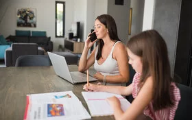 Mutter leidet unter Mental Load, weil sie neben der Arbeit auch noch Hausaufgaben mit ihrer Tochter machen muss.