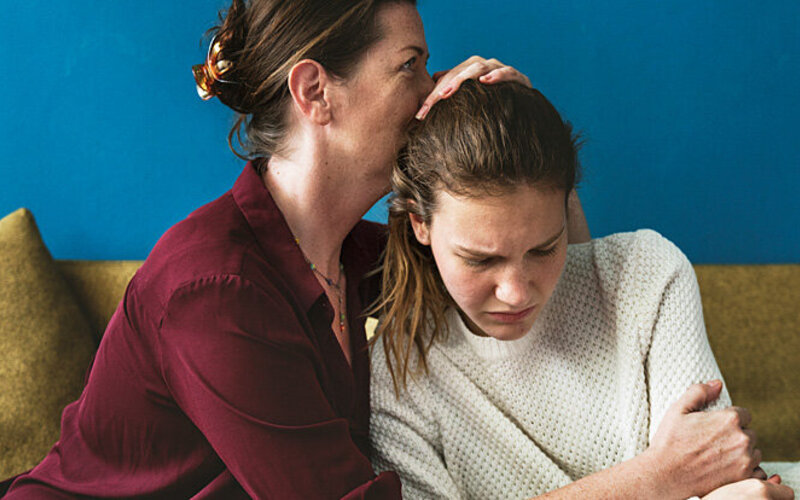 Eine Mutter tröstet ihre Tochter, die mit körperlichen Veränderungen in der Pubertät zu kämpfen hat.