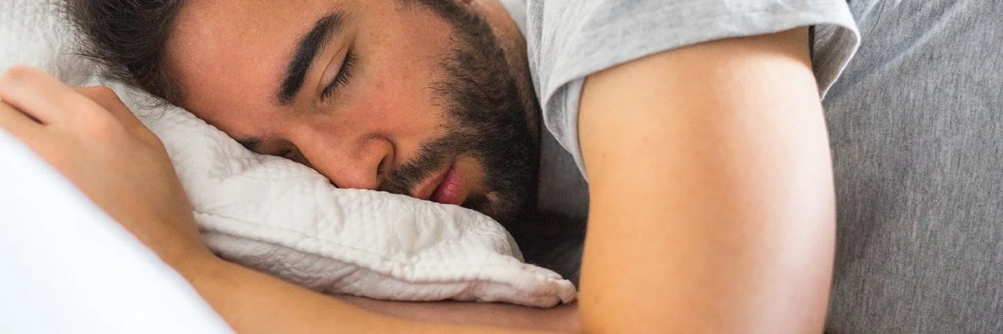 Junger Mann schläft in seinem Bett.