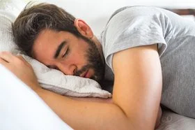 Junger Mann schläft in seinem Bett.