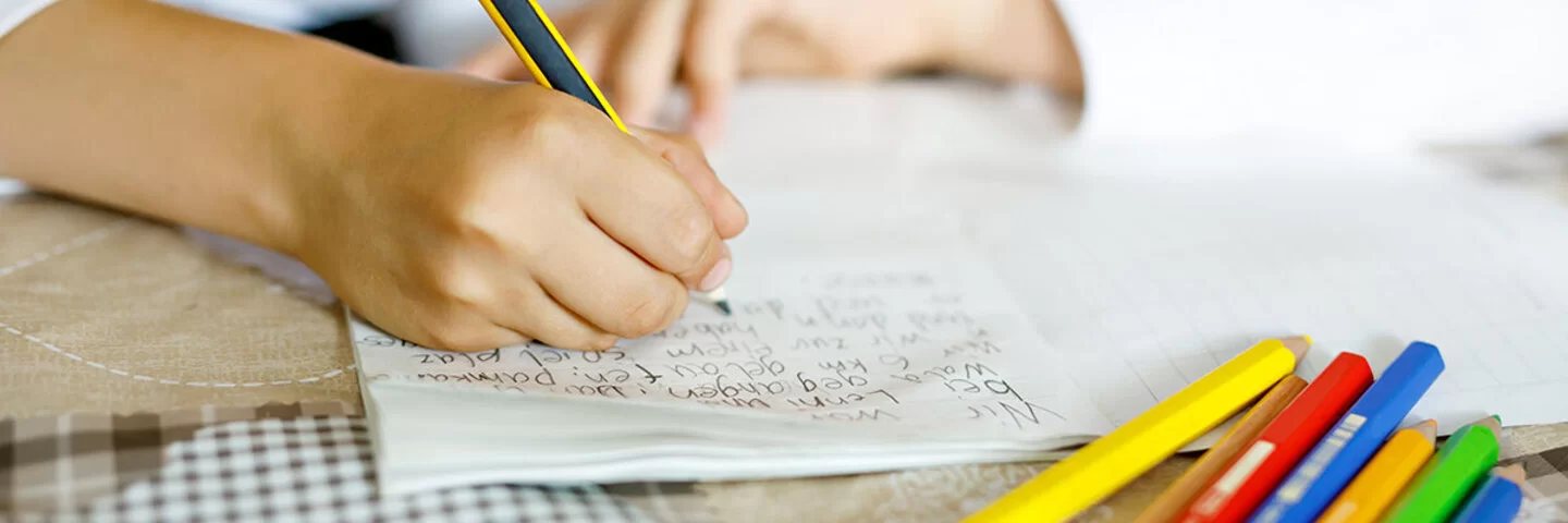 Ein Kind schreibt mit Handschrift seine Hausaufgaben.