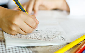 Ein Kind schreibt mit Handschrift seine Hausaufgaben.