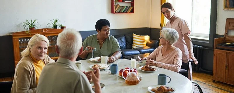 Eine Gruppe älterer Menschen werden von Pflegerin umsorgt.