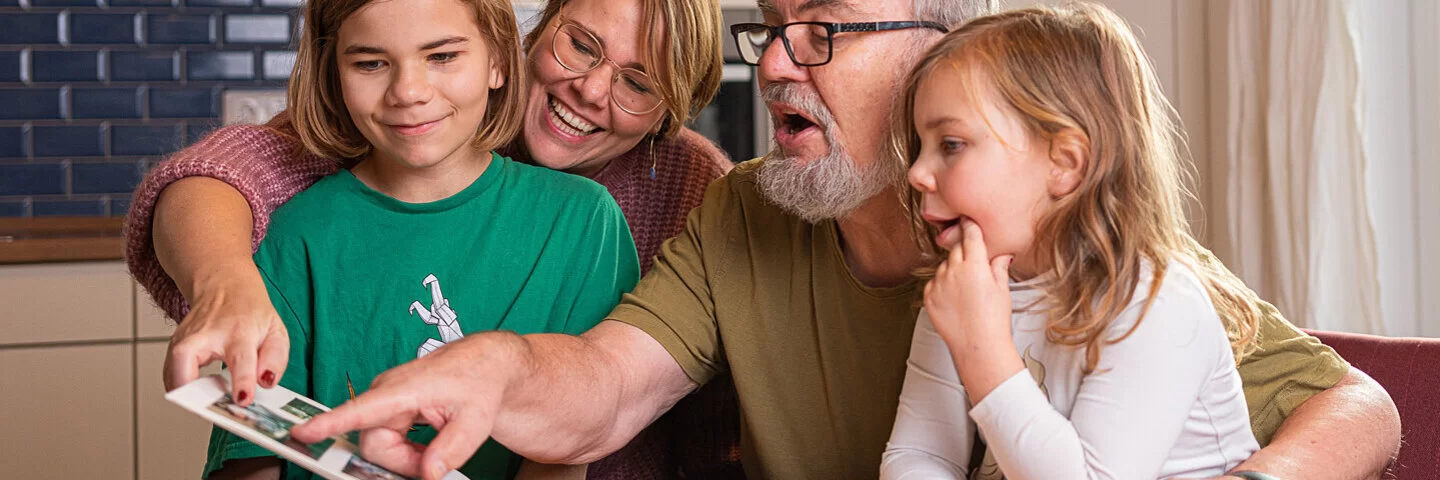 Familie liest ein Buch und unterstützt sich gegenseitig beim Älterwerden.