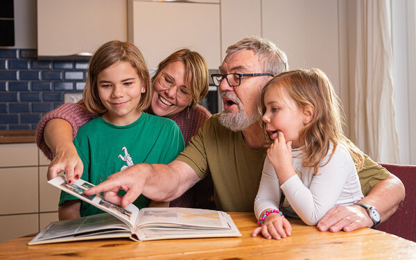 Familie liest ein Buch und unterstützt sich gegenseitig beim Älterwerden.