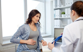 Eine Frau schwangere Frau sitzt gegenüber von ihrer Ärztin, die ihr Informationen zur Gürtelrose in der Schwangerschaft gibt.
