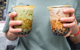 Zwei Hände tragen zwei ungesunde Bubble Tea in To-go-Bechern.