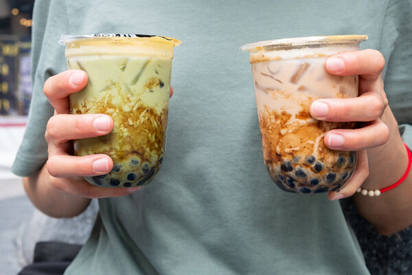 Zwei Hände tragen zwei ungesunde Bubble Tea in To-go-Bechern.