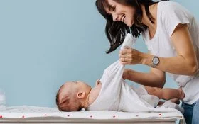 Eine Mutter zieht ihrem Kind einen Neurodermitis-Overall an. Diese Mittel lindern Beschwerden bei Neurodermitis.