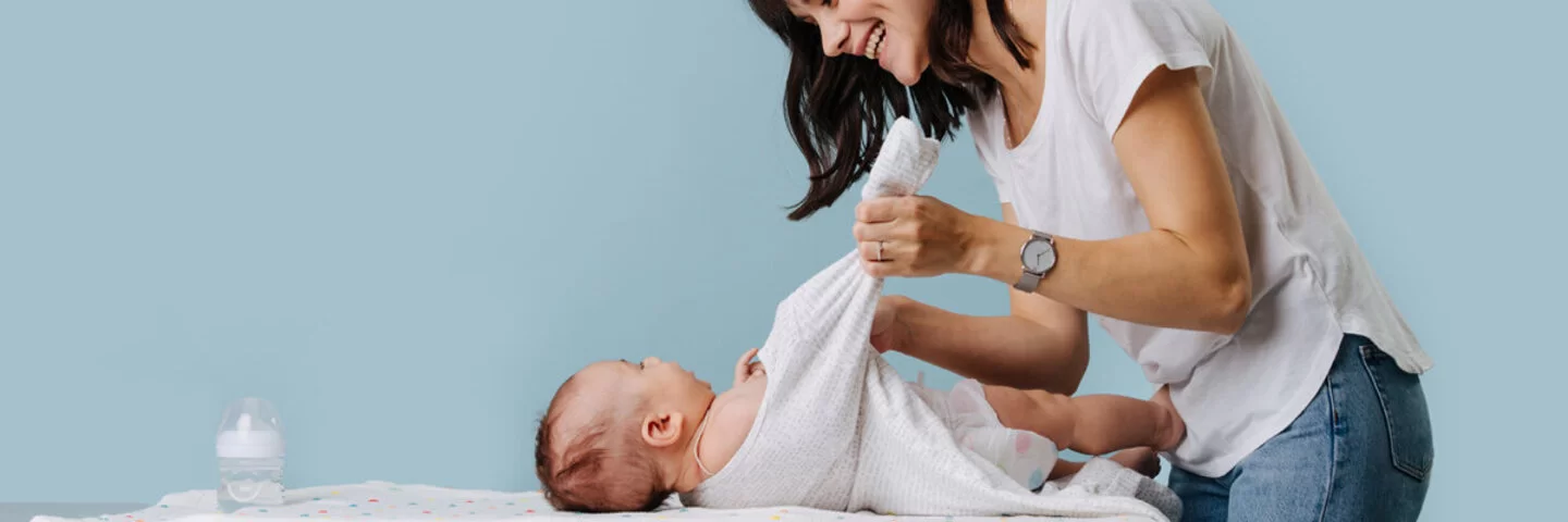 Eine Mutter zieht ihrem Kind einen Neurodermitis-Overall an. Diese Mittel lindern Beschwerden bei Neurodermitis.