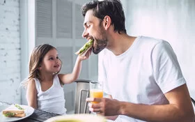 Ein junges Mädchen füttert ihren Vater.