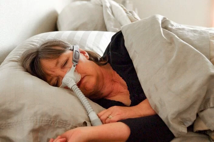 Eine Frau mit Beatmungsgerät schläft in ihrem Bett