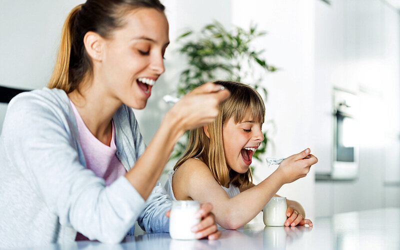 Mutter und Tochter essen gemeinsam selbstgemachten Joghurt.