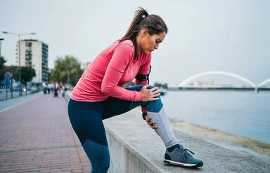 Eine Frau hält sich beim Joggen das Knie vor Schmerzen.