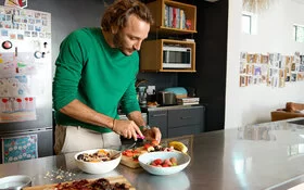 Ein Mann bereitet Obst und Vollkornprodukte zu. Das Wissen über gesunde Ernährung hat er aus einem Kurs der AOK.