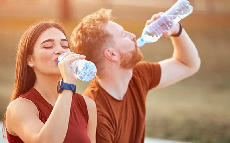 Ein Paar trinkt im Sommer ausreichend Wasser, um der durch den Klimawandel geschuldeten Hitze zu strotzen.