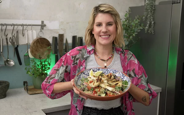 Felicitas Then hält einen Teller mit Quinoa-Salat und gegrillten Halloumi-Spießen in den Händen.