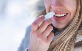 Eine Frau mit spröden Lippen pflegt ihre Lippen im Winter mit Lippenbalsam.