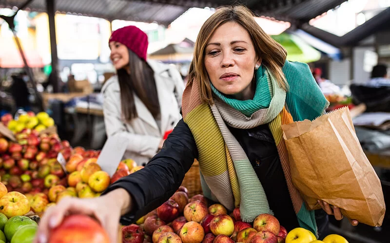 Eine Frau greift auf dem Markt zu frischem Obst, um einer TIA vorzubeugen.