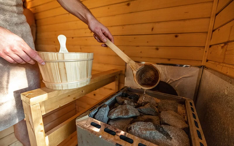 Eine Person macht in einer Sauna einen Aufguss.