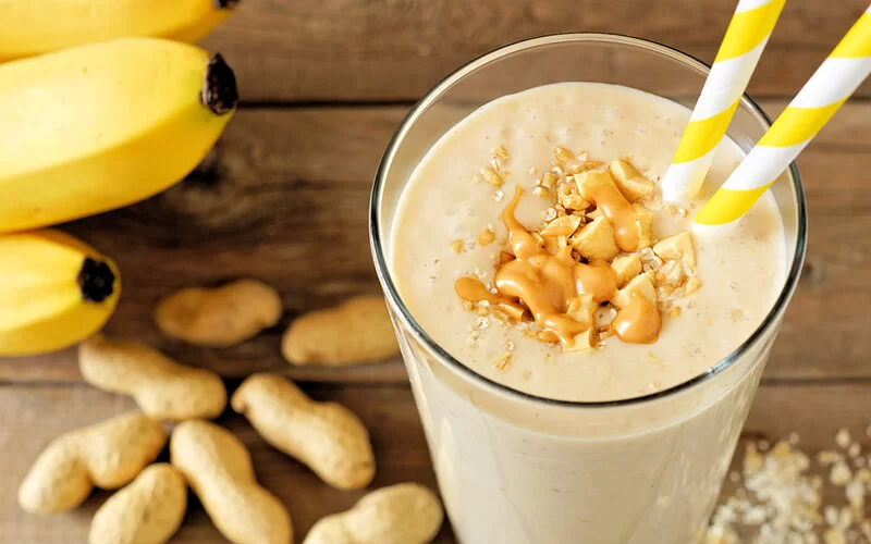 Ein Erdnussbutter-Shake mit Strohhalm steht auf einem Tisch.