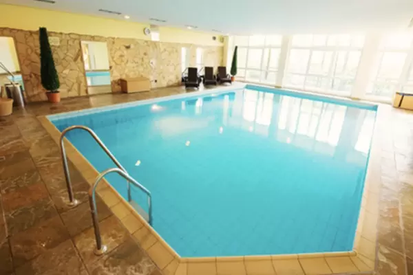 Das Schwimmbad im Hotel ist leer und man sieht eine helle Fensterfront.