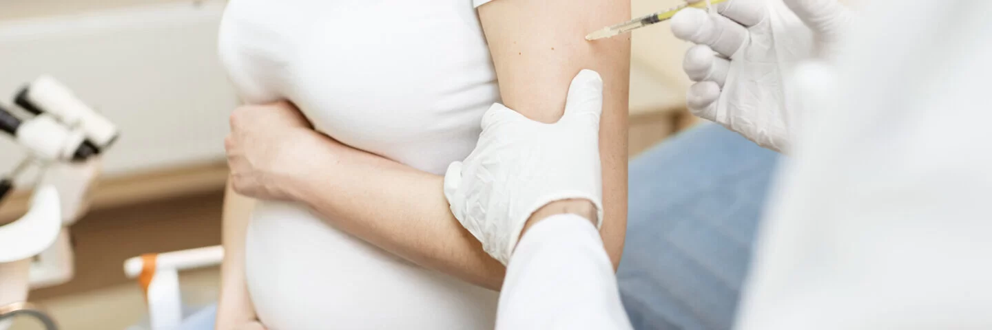 Ein Arzt impft eine schwangere Frau. Werdende Mütter sollten sich gegen Keuchhusten impfen lassen. 