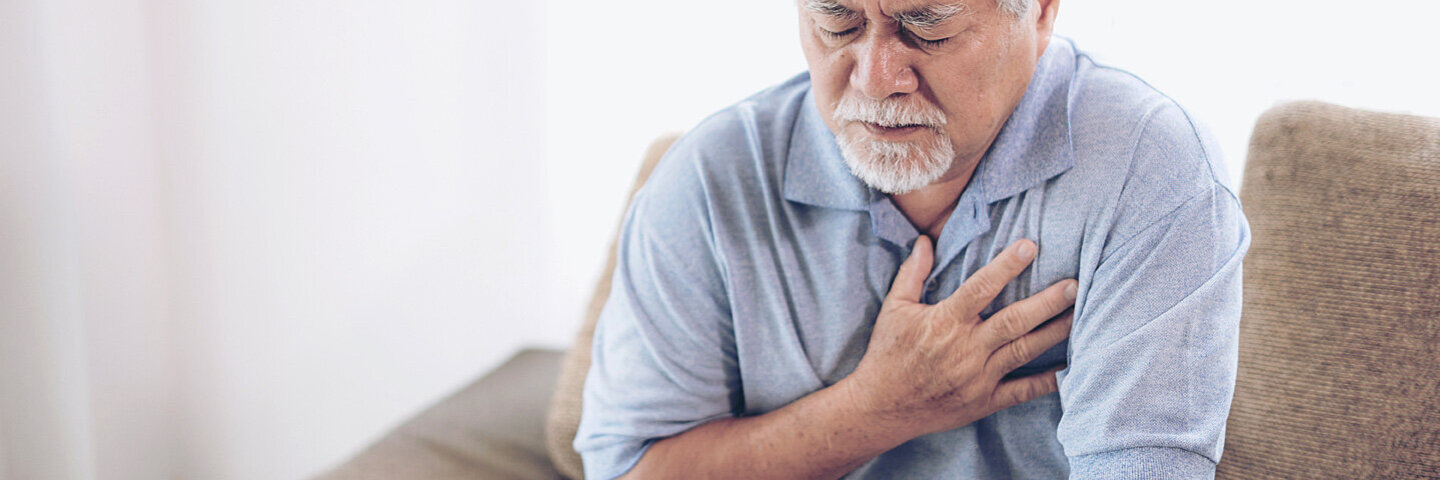 Ein älterer Mann fast sich unter Schmerzen ans Herz, er leidet unter Arteriosklerose.