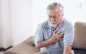 Ein älterer Mann fast sich unter Schmerzen ans Herz, er leidet unter Arteriosklerose.