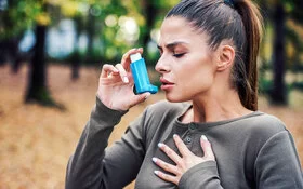 Eine Frau, welche an Asthma erkrankt ist, benutzt ein Asthmaspray.