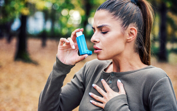 Eine Frau, welche an Asthma erkrankt ist, benutzt ein Asthmaspray.