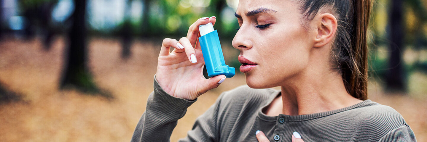 Eine Frau, welche an Asthma erkrankt ist, benutzt ein Asthmaspray.