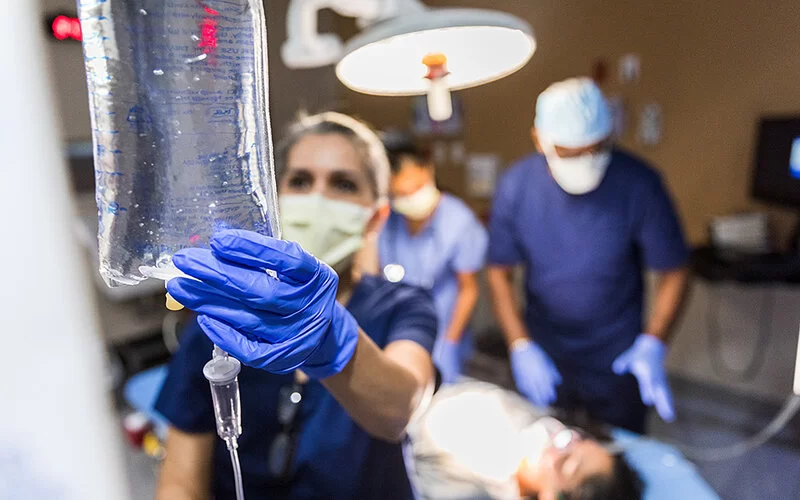 Ärztin kontrolliert den Tropf einer Patientin.